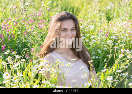 Mädchen sitzt auf Wiese mit Wildblumen Stockfoto