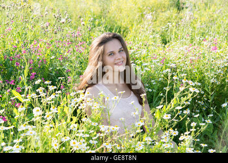 Mädchen sitzt auf Wiese mit Wildblumen Stockfoto