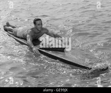 Champion Surfer/Paddler Gene "Tarzan" Smith auf hölzernen Surfbrett während fast 100 Mile Paddel von Honolulu nach Kauai (Hawaii-Territorium). Smith ging auf seine Welt Rekord Paddel am 14. Oktober 1940 von Oahu Kaena Point auf einem Surfbrett 14 Fuß in Bereichen der raue Brandung in Richtung zu seinem Bestimmungsort auf der Insel Kauai, 90 Meilen entfernt. Nach 30 Stunden Paddeln über was als einer der gefährlichsten Kanäle in der hawaiischen galt Gewässern, Gene in Koloa angekommen, ungefähr fünf Meilen westlich von seinem Ziel, Nawiliwili Hafen, dass Kurs von starken Winden weggeblasen. Stockfoto