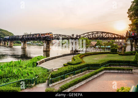 Züge für Reisen auf der alten Brücke über den River Kwai Yai bei Sonnenuntergang laufen einen historischen Sehenswürdigkeiten während des 2. Weltkrieges ist die Stockfoto