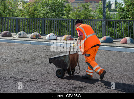 Berlin, Deutschland. 22. Juli 2016. Ein Straßenarbeiter schiebt eine Schubkarre mit Asphalt über Momumenten Brücke in Berlin, Deutschland, 22. Juli 2016. Foto: Wolfram Kastl/Dpa/Alamy Live-Nachrichten Stockfoto