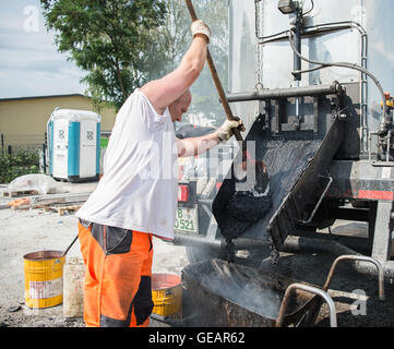 Berlin, Deutschland. 22. Juli 2016. Ein Straßenarbeiter gießt Asphalt in eine Schubkarre auf Momumenten Brücke in Berlin, Deutschland, 22. Juli 2016. Foto: Wolfram Kastl/Dpa/Alamy Live-Nachrichten Stockfoto