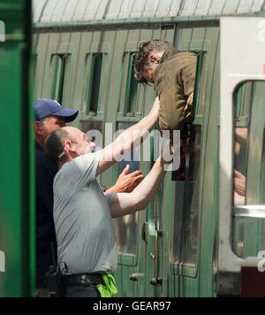 Swanage, Dorset, UK-Station.  25. Juli 2016. Verfilmung von Dünkirchen (Bogeda Bay) in Swanage Station in Dorset.  Harry Styles wird in dem Zugfenster stecken und muss geholfen werden durch ein Mitglied der Besatzung zu befreien, während der Dreharbeiten zu einer Szene in Swanage Station, die als Woking verdoppelt, wo He Swiggs Bier und isst Äpfel während hängen aus dem Zugfenster bei der Ankunft auf der Plattform.  Foto von Graham Hunt/Alamy Live-Nachrichten Stockfoto