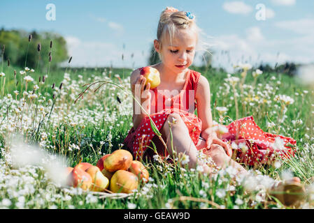 GRL sitzen in Blumenwiese mit Äpfeln Stockfoto