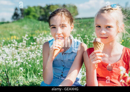 Zwei Mädchen auf Wiese essen Eiscreme-Kegel Stockfoto