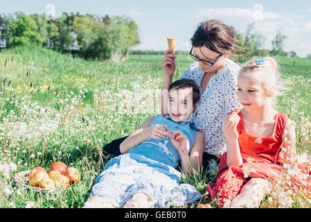 Mutter und zwei Mädchen auf Wiese entspannen Stockfoto