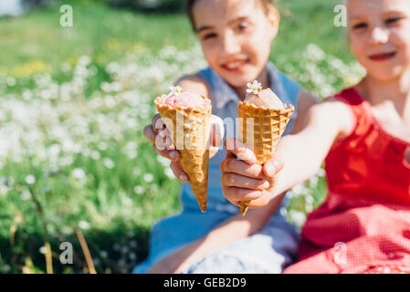 Zwei Mädchen auf Wiese mit Eiswaffeln Stockfoto
