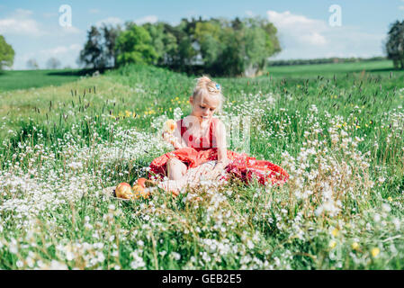 GRL sitzen in Blumenwiese mit Äpfeln Stockfoto