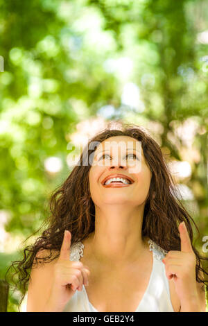 Edle Reife Frau lächelt während suchen und mit beiden Händen nach oben zeigend. Stockfoto