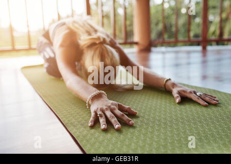Frau nach vorne Strecken, eine Yoga-Pose auf Gymnastikmatte durchführen. Fitness Frauen Durchführung Balasana Yoga im Fitness-Studio, konzentrieren sich auf Hände Stockfoto
