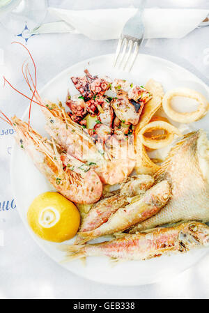 Gekochter Fisch auf Teller mit Zitrone und Wein Stockfoto