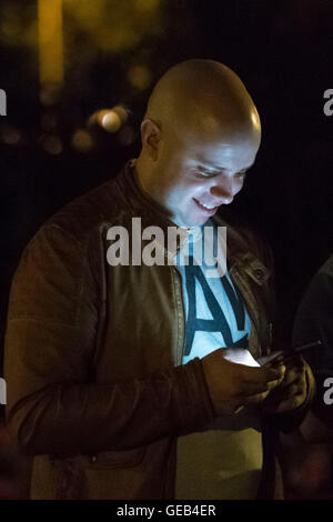 Ein Mann spielt Pokemon gehen auf seinem Handy in der Nacht. Stockfoto