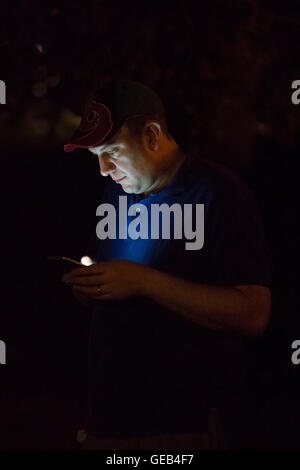 Ein Mann spielt Pokemon gehen auf seinem Handy in der Nacht. Stockfoto