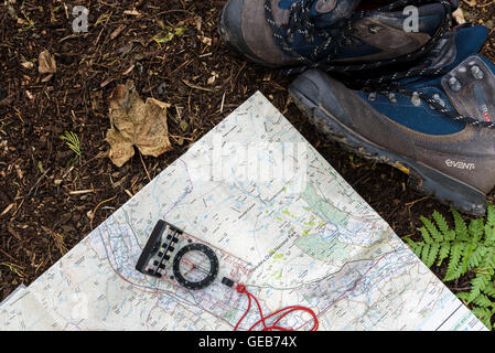 Paar Wanderstiefel mit Karte und Kompass, auf einem Waldboden. Luftaufnahme von oben. Stockfoto