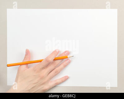 Draufsicht der weiblichen Hand mit Bleistift auf Blankopapier Blatt. Auf Karton Hintergrund Stockfoto