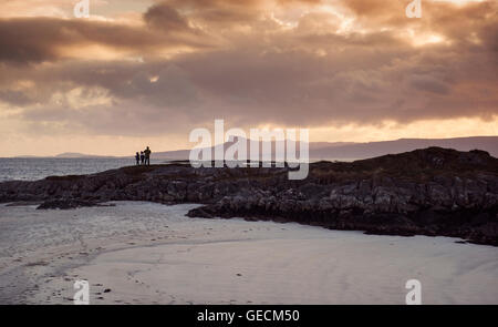 Familie wacht Sonnenuntergang über den Inseln Eigg, einer der kleinen Inseln der Inneren Hebriden, von Arisaig in Schottland Stockfoto