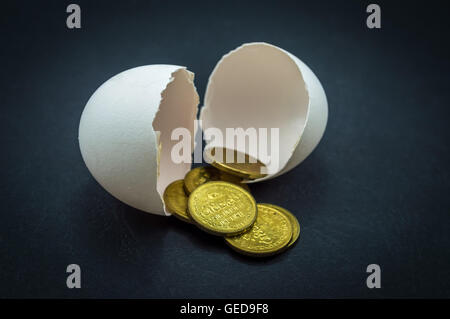 Eierschalen und Geld Münzen in einem schwarzen Hintergrund Stockfoto