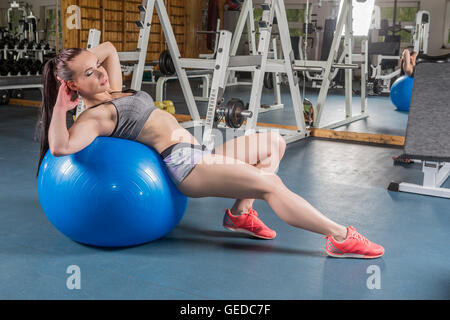 Eine muskulöse junge Frauen in einer Turnhalle mit einem Gymnastikball trainieren (oder Sport) Stockfoto