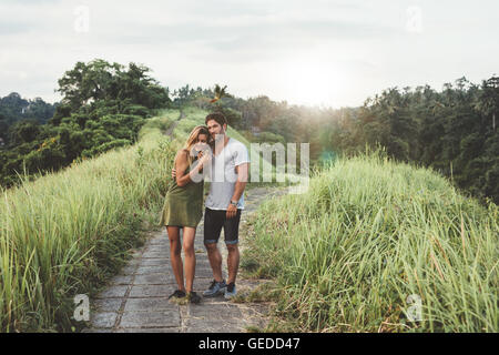 Im Freien Schuss der jungen Paare, die zusammen über Landstraße. Junger Mann und Frau in der Liebe, ein Spaziergang in der Wiese. Stockfoto