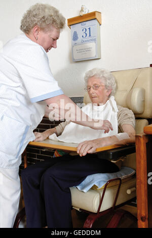 Hausmeister Beihilfe einen Rentner im Rollstuhl in einem Pflegeheim Stockfoto