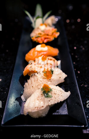 Gericht der verschiedenen Sushi-Arten, selektiven Fokus-Punkt mit blur Schärfentiefe-Effekt, düstere Atmosphäre Stockfoto