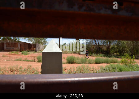 Eine Lücke in der aktuellen Metal Grenzmauer zeigt Jugendliche in Mexiko und die ursprüngliche konkrete Grenzstein in Naco, Arizona, USA. Stockfoto