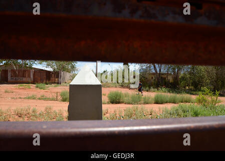 Eine Lücke in der aktuellen Metal Grenzmauer zeigt Jugendliche in Mexiko und die ursprüngliche konkrete Grenzstein in Naco, Arizona, USA. Stockfoto