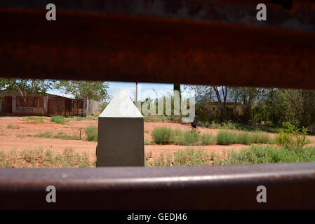 Eine Lücke in der aktuellen Metal Grenzmauer zeigt Jugendliche in Mexiko und die ursprüngliche konkrete Grenzstein in Naco, Arizona, USA. Stockfoto