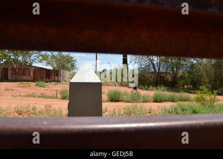 Eine Lücke in der aktuellen Metal Grenzmauer zeigt Jugendliche in Mexiko und die ursprüngliche konkrete Grenzstein in Naco, Arizona, USA. Stockfoto