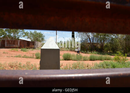 Eine Lücke in der aktuellen Metal Grenzmauer zeigt Jugendliche in Mexiko und die ursprüngliche konkrete Grenzstein in Naco, Arizona, USA. Stockfoto