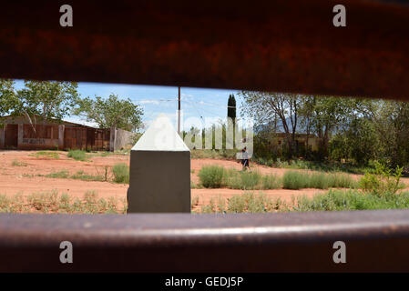 Eine Lücke in der aktuellen Metal Grenzmauer zeigt Jugendliche in Mexiko und die ursprüngliche konkrete Grenzstein in Naco, Arizona, USA. Stockfoto