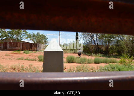 Eine Lücke in der aktuellen Metal Grenzmauer zeigt Jugendliche in Mexiko und die ursprüngliche konkrete Grenzstein in Naco, Arizona, USA. Stockfoto