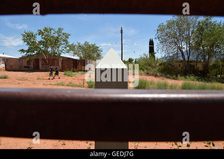 Eine Lücke in der aktuellen Metal Grenzmauer zeigt Jugendliche in Mexiko und die ursprüngliche konkrete Grenzstein in Naco, Arizona, USA. Stockfoto