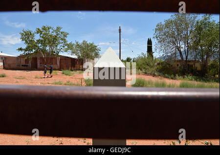 Eine Lücke in der aktuellen Metal Grenzmauer zeigt Jugendliche in Mexiko und die ursprüngliche konkrete Grenzstein in Naco, Arizona, USA. Stockfoto