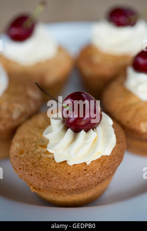 Mandel Cupcakes oder Brötchen mit Mandelscheiben an der Spitze, mit Buttercreme Rohrleitungen und eine ganze Sahnehäubchen fertig. Schuss hautnah Stockfoto