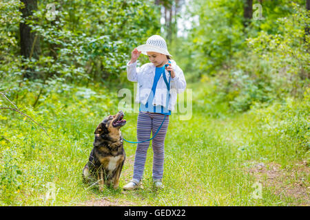 Kleine Mädchen spielen mit Hund im Wald Stockfoto