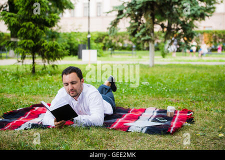 hübscher junger Geschäftsmann Buch liegen im park Stockfoto