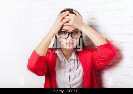 Geschäftsfrau halten Hände am Kopf, Schmerz, Schmerzen depressiv tragen rote Jacke Gläser betont Stockfoto