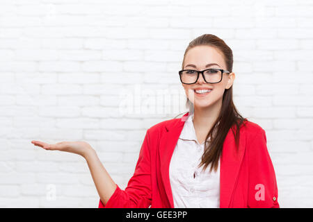 Geschäftsfrau offenen Handfläche Handgeste, Raum tragen rote Jacke Gläser Lächeln zu kopieren Stockfoto