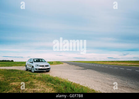 Gomel, Weißrussland - 13. Juni 2016: Volkswagen Polo Parkplätze am Straßenrand der Landstraße auf einem Hintergrund von Frühlingsgrün Felder Stockfoto