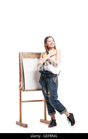 Junge lächelnde Frau stehend auf Staffelei, Palette umarmt Stockfoto