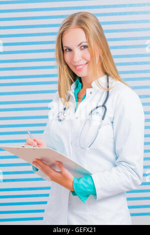 Krankenschwester mit langen blonden Haaren und einem Stethoskop in Uniform in die Kamera Lächeln Stockfoto