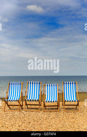 Reihe von vier leere Liegestühle auf einem Kiesstrand an der sonnigen Küste in Kent, UK Stockfoto