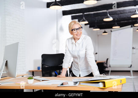 Porträt von eine schöne Reife lächelnd Geschäftsfrau, stehen in der Nähe ihres Arbeitsplatzes Stockfoto