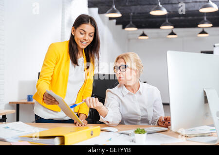Zwei lächelnde Geschäftsfrauen in Zusammenarbeit mit pc am Tisch im Büro Stockfoto