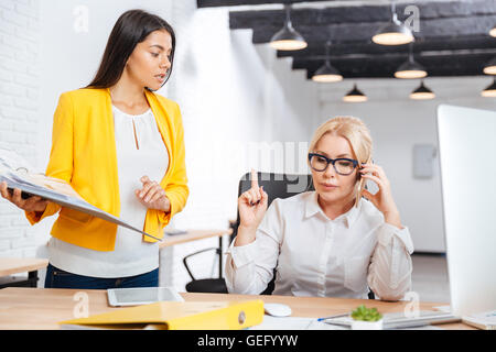 Zwei intelligente Geschäftsfrauen besprechen Ideen am Tisch im Büro Stockfoto