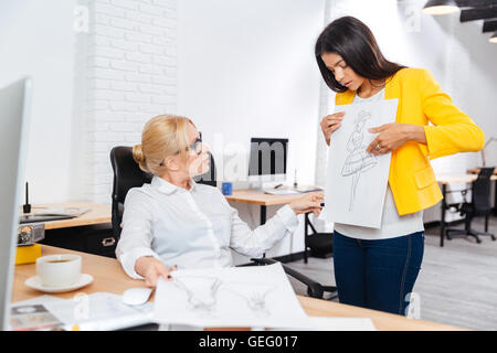 Team von zwei schweren weiblichen Architekten diskutieren Skizzen im Büro Stockfoto