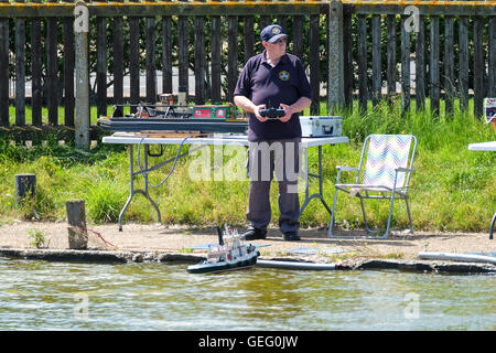 Mann mit Fernbedienung und Boot auf See mit Booten bei Great Yarmouth Stockfoto