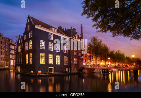 Schöne Nacht in Amsterdam. Nacht Beleuchtung von Gebäuden und Boote in der Nähe der Wasser in den Kanal. Stockfoto