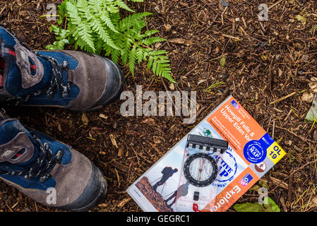 Paar Wanderstiefel mit Karte und Kompass, auf einem Waldboden. Luftaufnahme von oben. Stockfoto